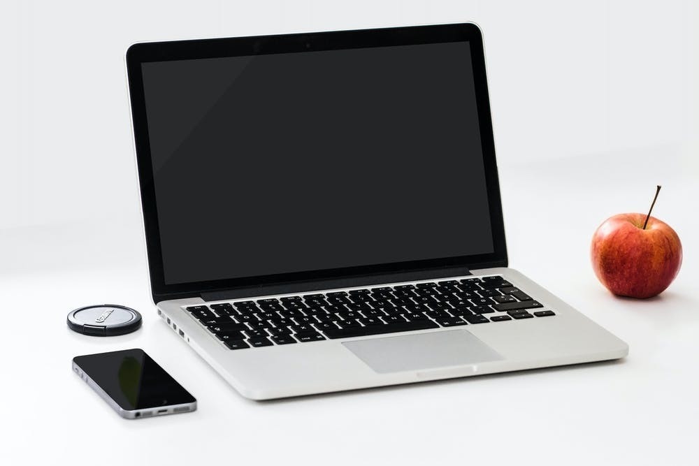 laptop, smart phone and apple on a white desk 